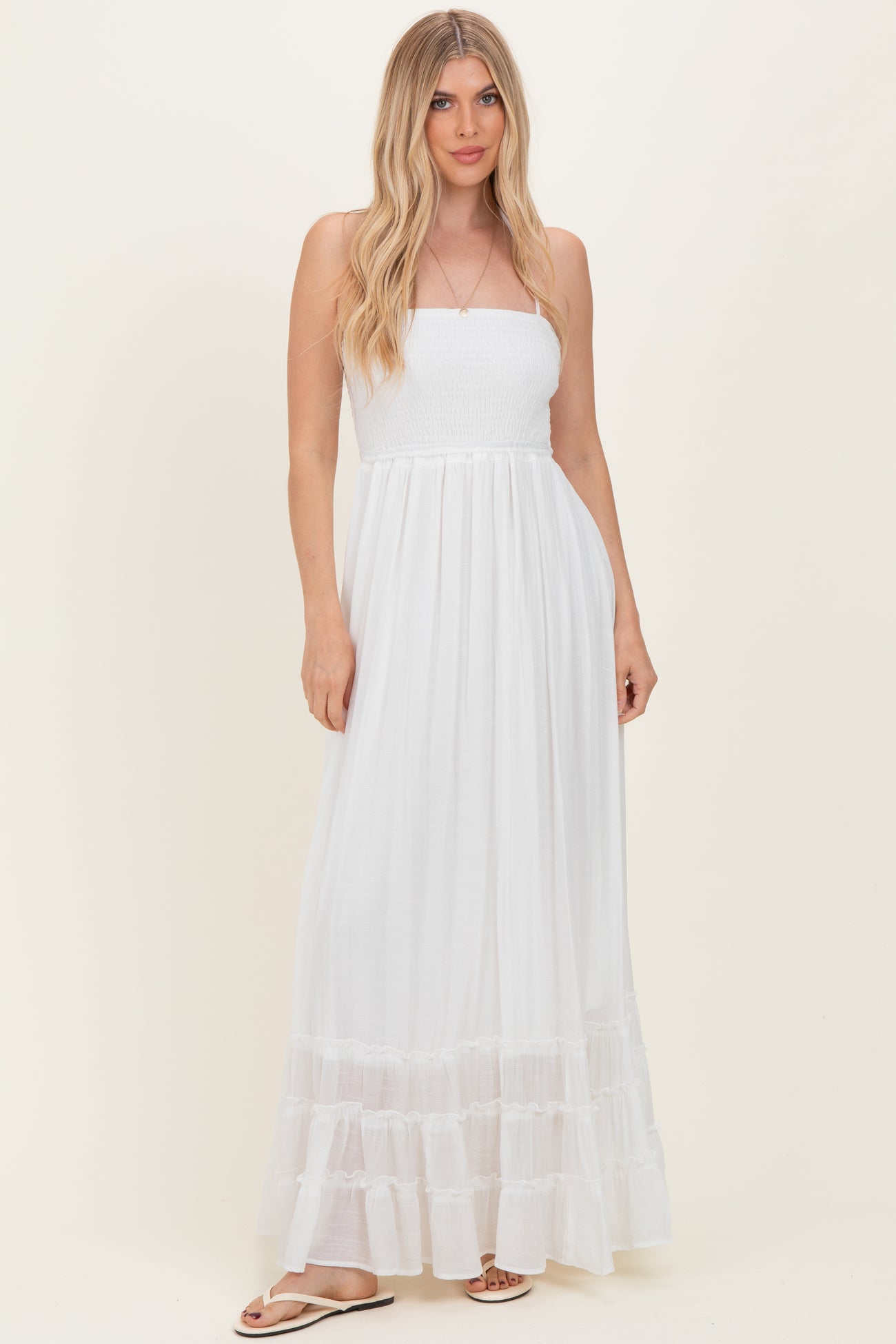 woman wearing a white strapless maxi dress with smocked bodice and tiered ruffle hem