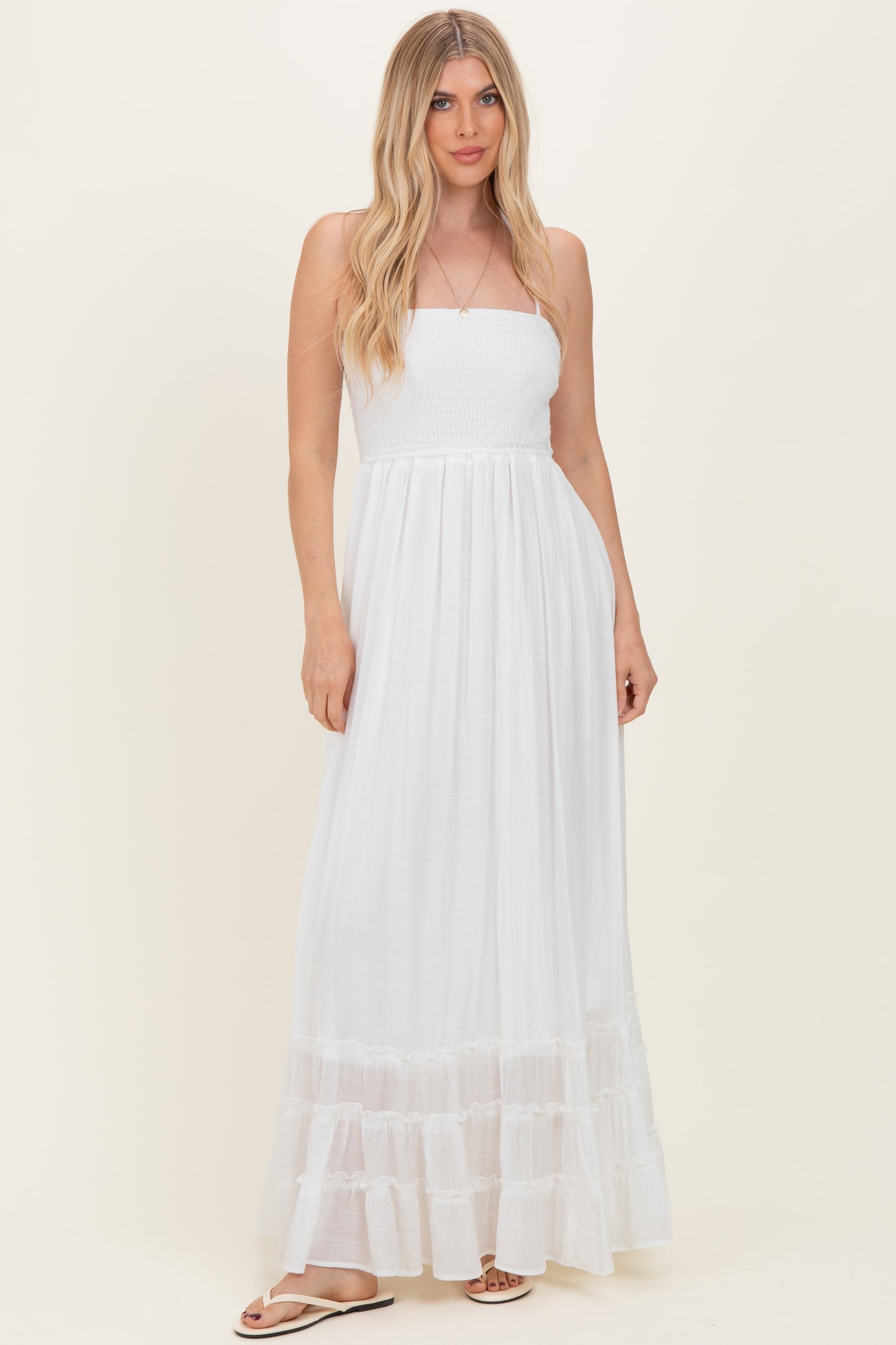 woman wearing a white strapless maxi dress with smocked bodice and tiered ruffle hem