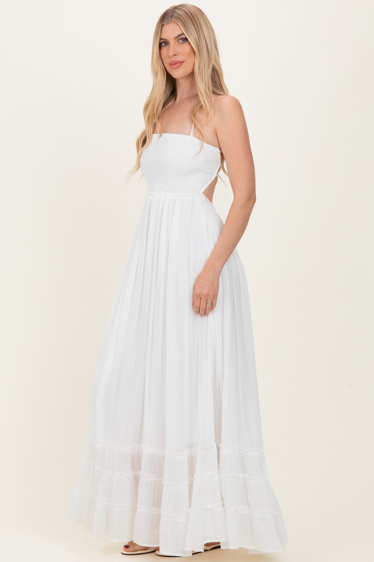 woman wearing a white strapless maxi dress with smocked bodice and ruffled hemline
