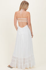 woman wearing a white halter neck maxi dress with a tiered skirt and open back detail
