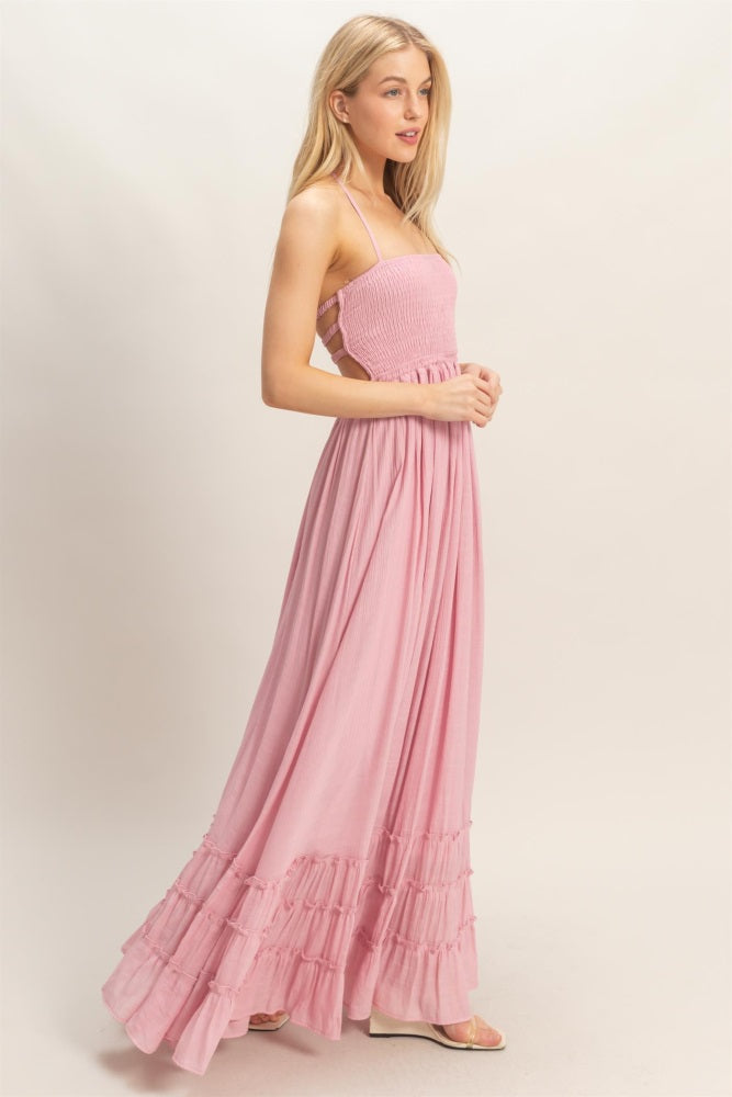 woman wearing a pink smocked maxi dress with ruffled hemline and spaghetti straps
