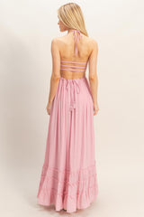 woman wearing a pink backless maxi dress with a halter neck and ruffled hem, showing a relaxed fit