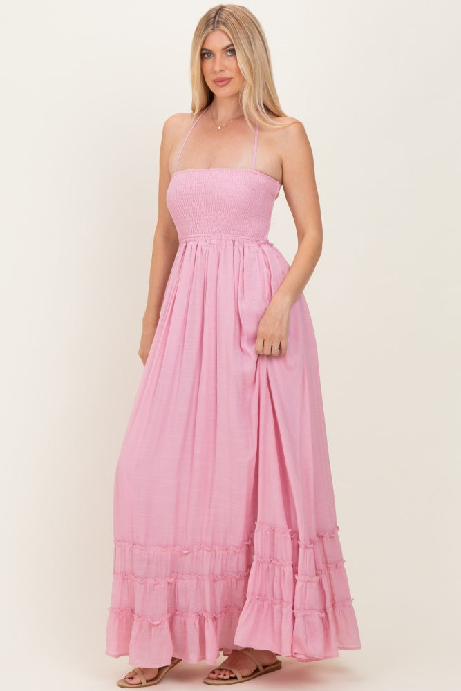 woman wearing a light pink strapless maxi dress with a smocked bodice and ruffled hem details