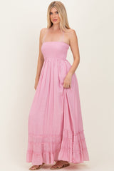 woman wearing a light pink strapless maxi dress with a smocked bodice and ruffled hem details