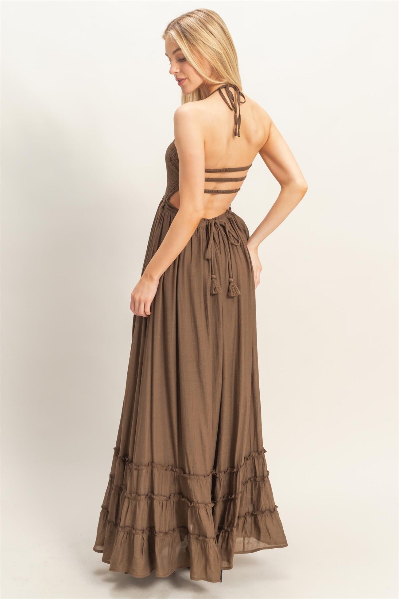 woman wearing a brown maxi dress with a strappy back and ruffle hem details