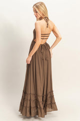woman wearing a brown maxi dress with a strappy back and ruffle hem details