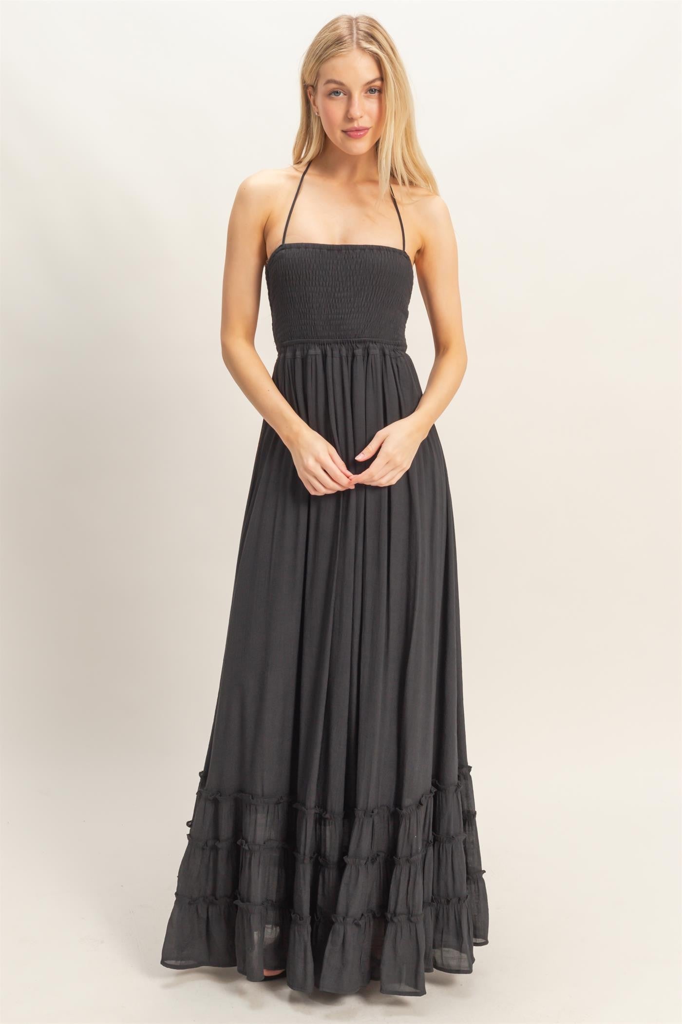 woman wearing a black strapless maxi dress with smocked bodice and tiered ruffle hem