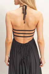 woman wearing a black halter dress with crisscross back straps and a tied waist detail