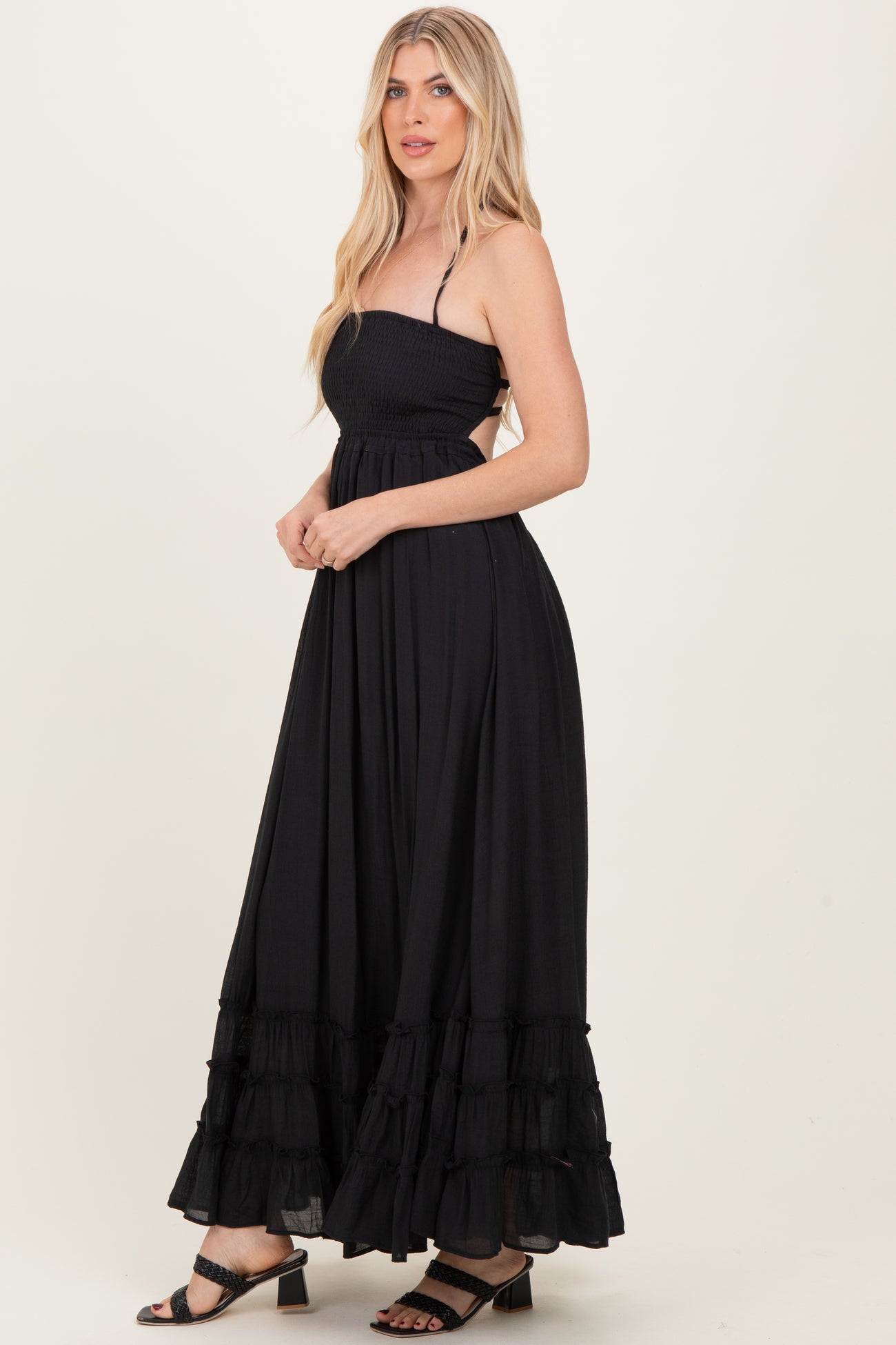 woman wearing a black strapless maxi dress with smocked bodice and tiered ruffles at the hem