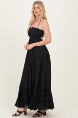 woman wearing a black strapless maxi dress with smocked bodice and tiered ruffles at the hem
