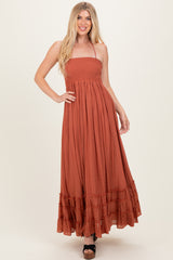 woman wearing a rust brown off-the-shoulder maxi dress with a smocked bodice and ruffled hem