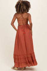 woman wearing an rust-colored maternity maxi dress with a tiered skirt and back tie detail