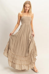 woman wearing a beige spaghetti strap maxi dress with a smocked bodice and ruffled hemline
