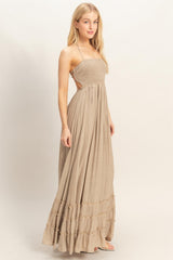 woman wearing a beige maxi dress with a smocked bodice and tiered ruffle detailing at the hem