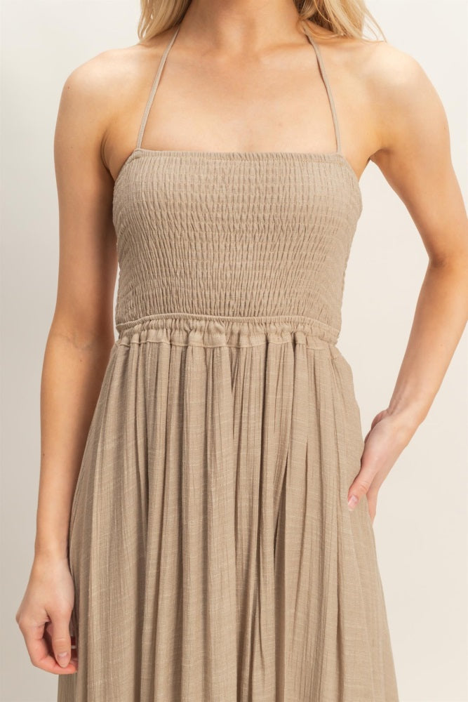 woman wearing a beige strapless maxi dress with smocked bodice and gathered waist detail
