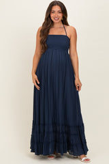 woman wearing a navy blue maternity maxi dress with a smocked bodice and tiered ruffles, showing baby bump