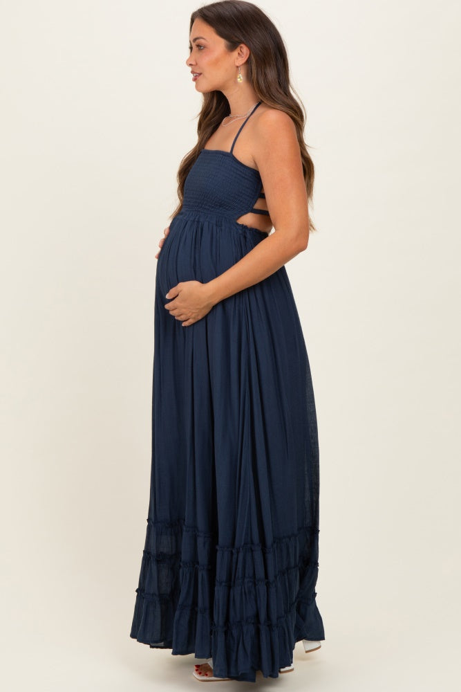woman wearing a navy blue maternity maxi dress with a smocked bodice and tiered ruffle hem, showcasing her baby bump