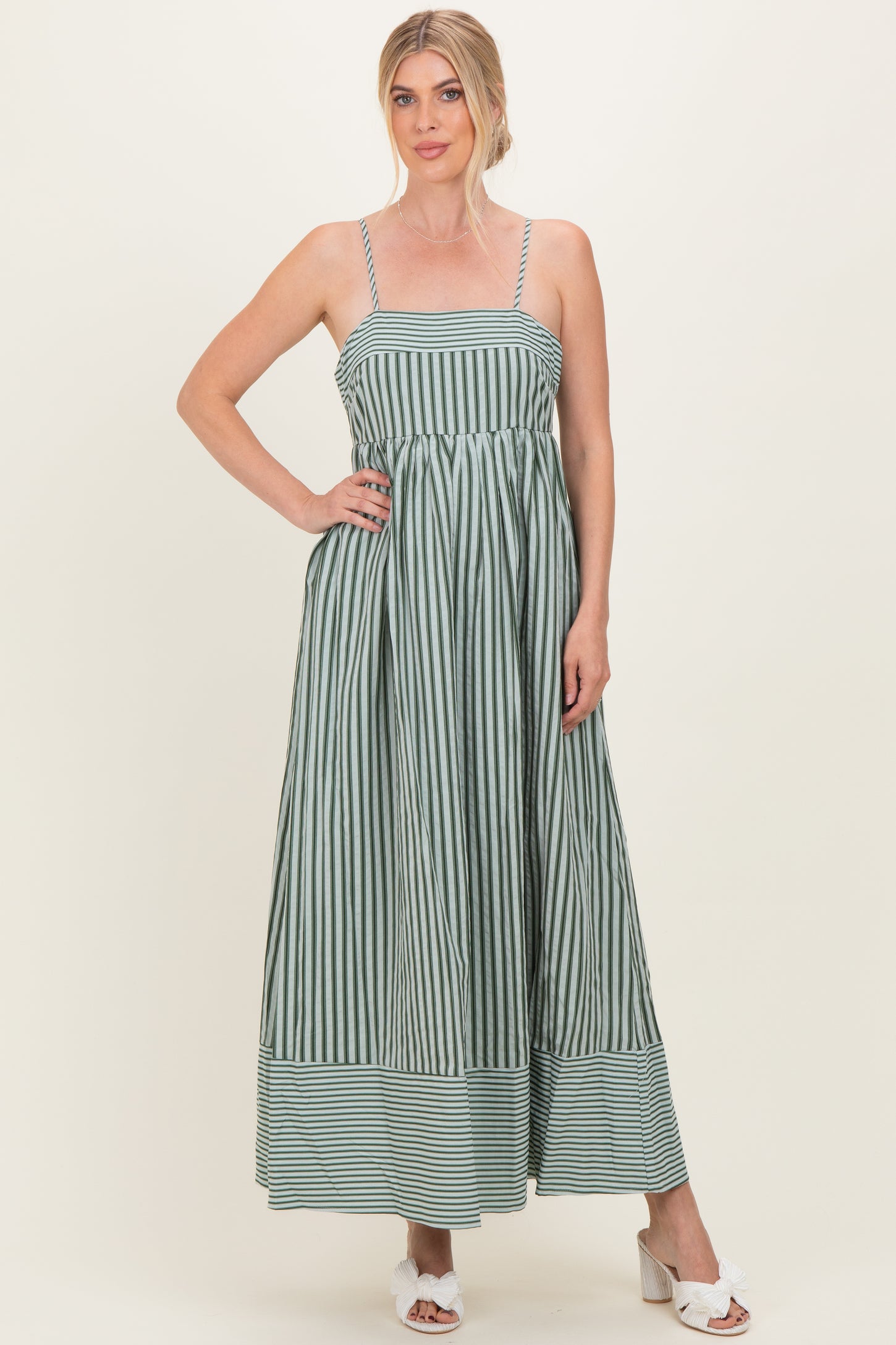woman wearing a green and white striped maxi dress with adjustable straps and a gathered waist