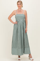 woman wearing a green and white striped maxi dress with adjustable straps and a gathered waist