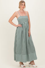 woman wearing a green and white striped maxi dress with thin straps and a fitted bodice