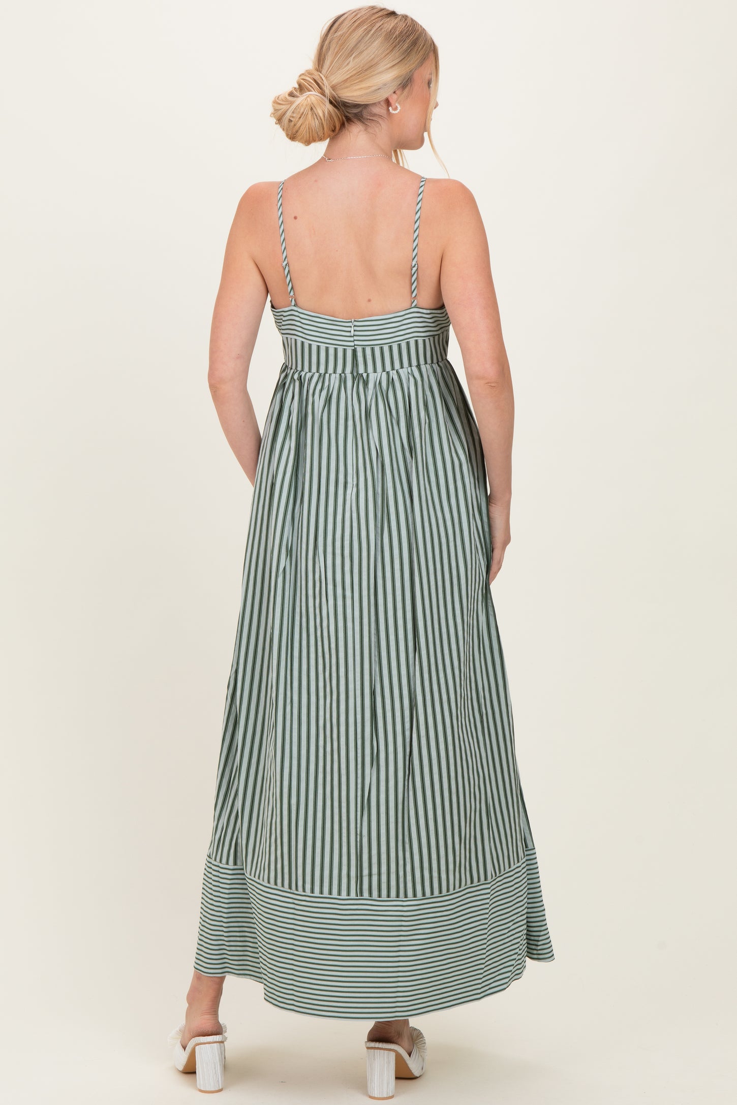 woman wearing a green and white striped maxi dress with a back tie detail and a flowy silhouette