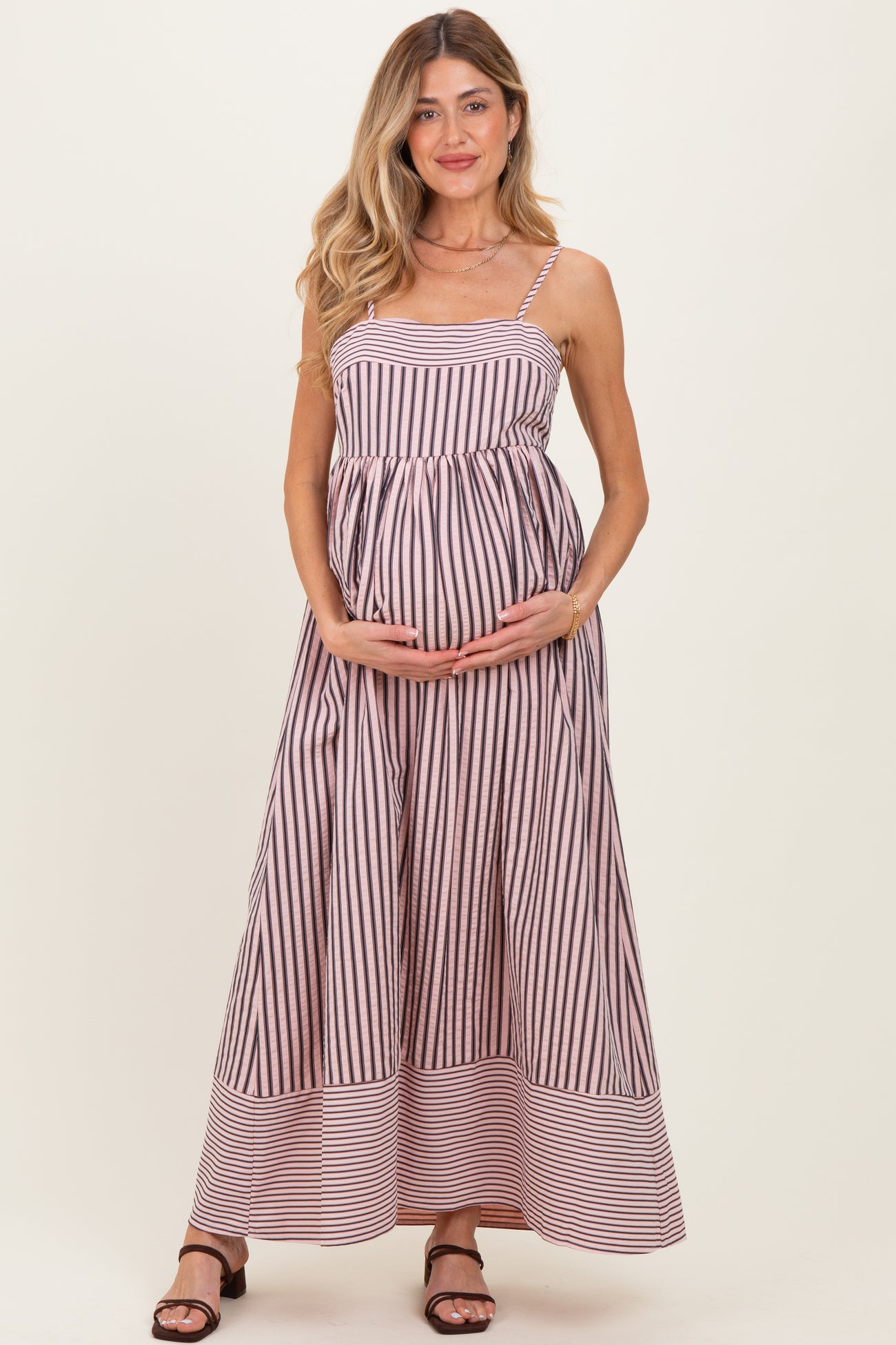 woman wearing a striped maternity maxi dress and holding her baby bump