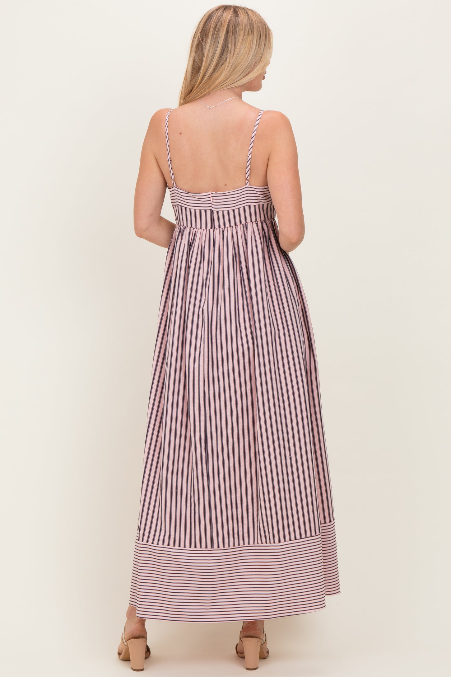 woman wearing a back view of a striped maxi dress with thin straps and a fitted bodice