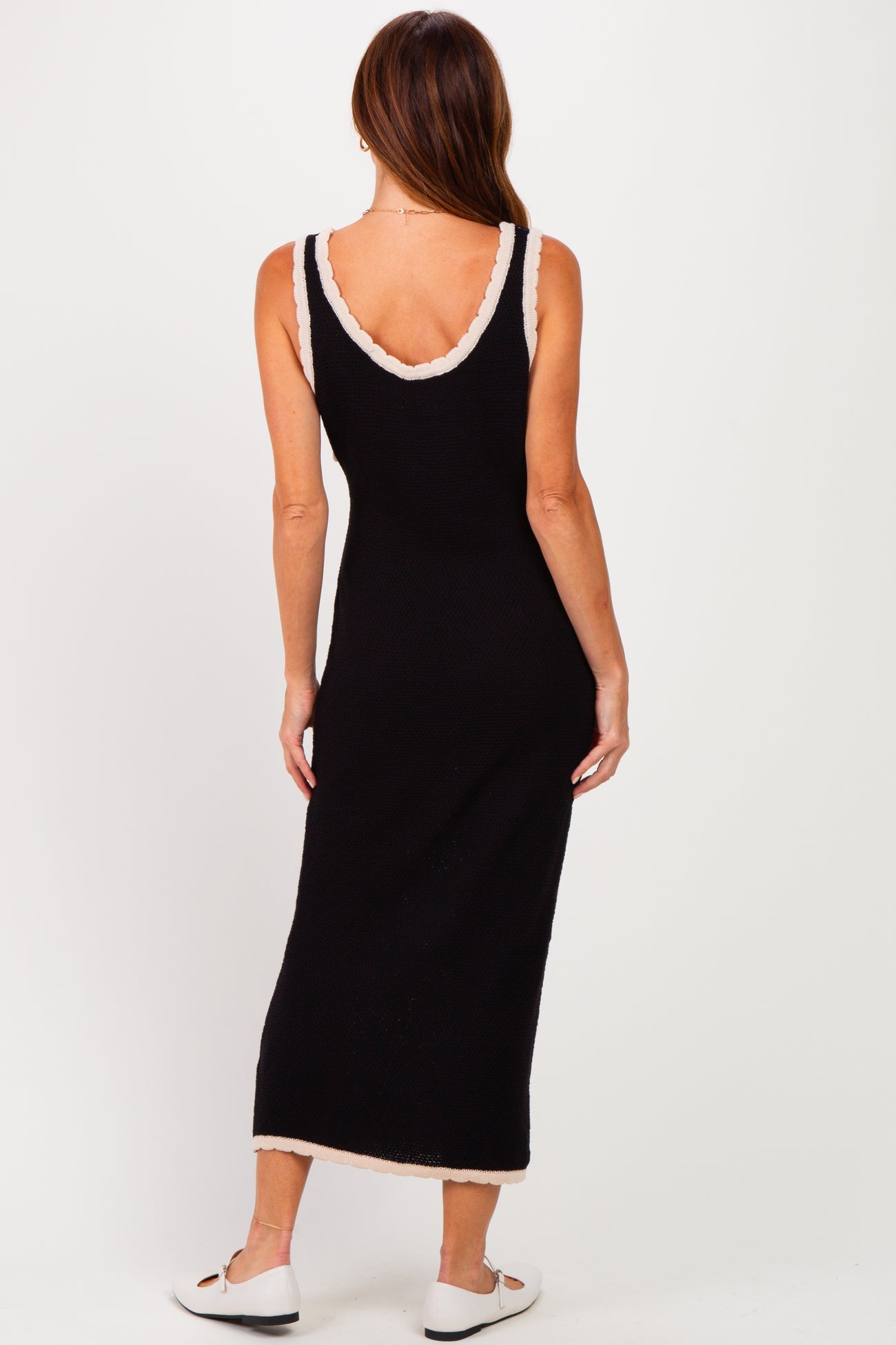 woman wearing a black sleeveless maxi dress with cream trim details, showing the back view