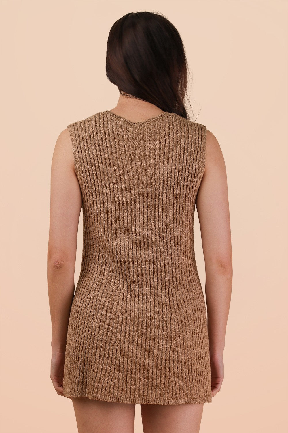 woman wearing a beige sleeveless ribbed knit dress, showing the back view against a light background