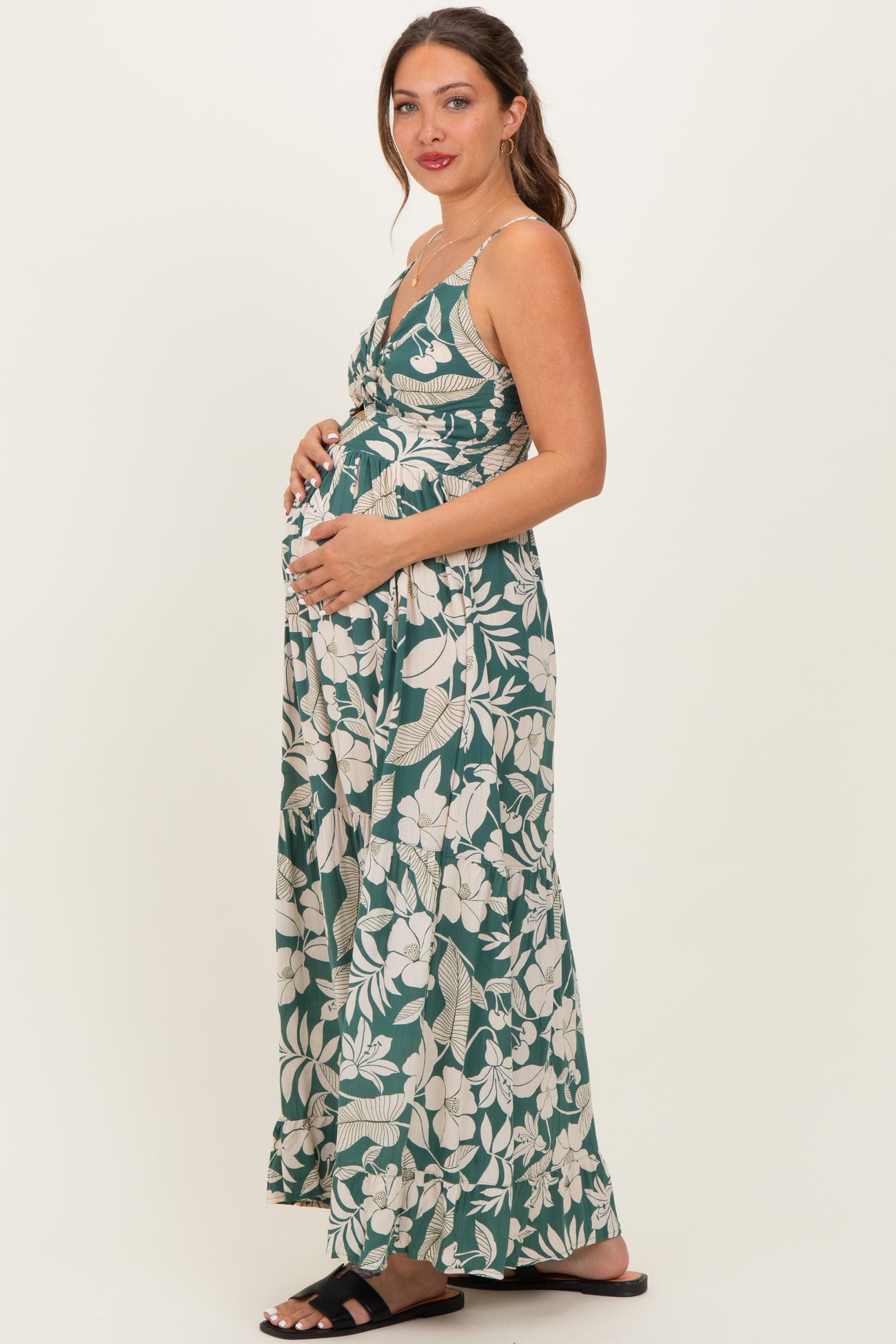 woman wearing a green floral maternity maxi dress and holding her baby bump