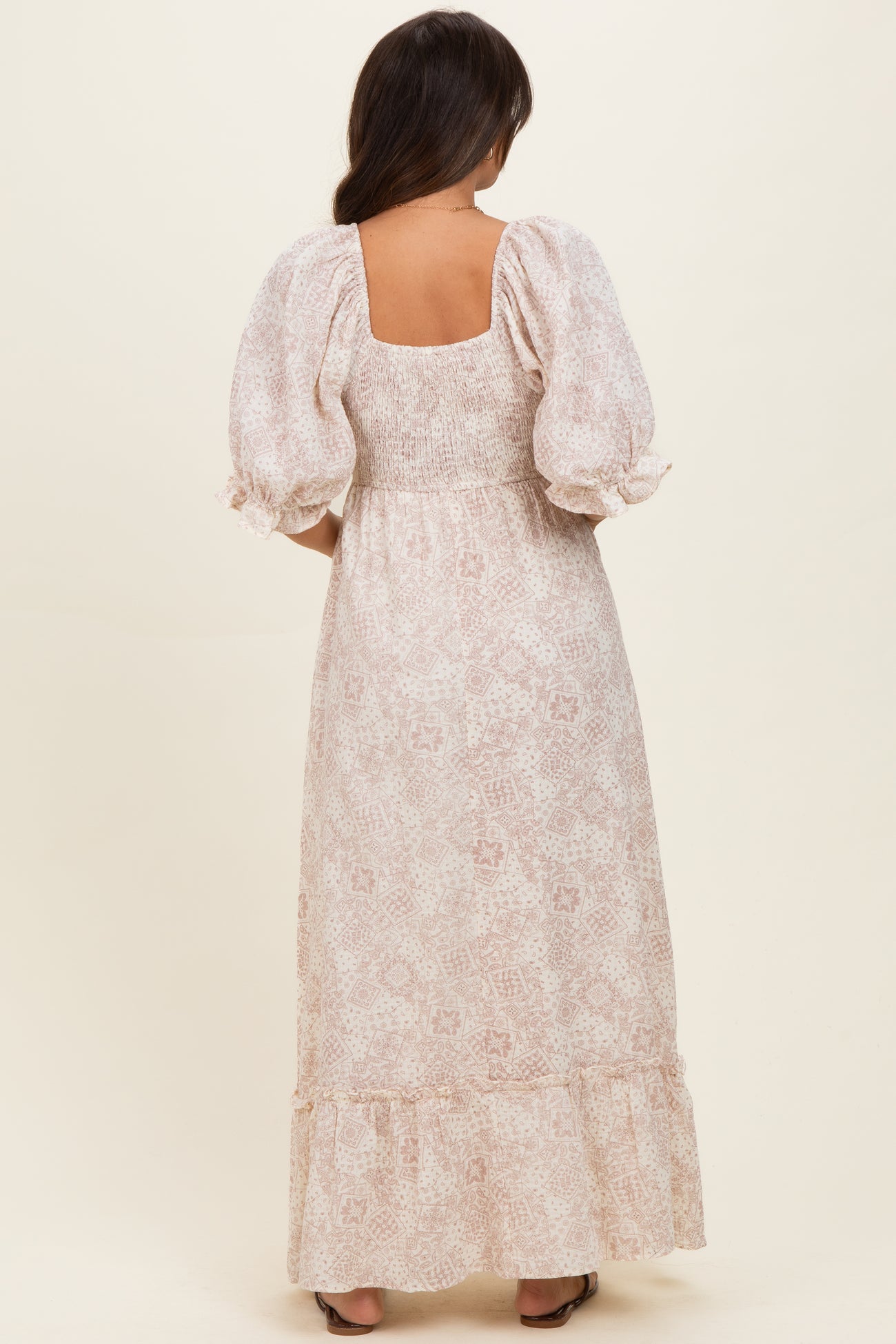 woman wearing a pink floral maternity maxi dress with puff sleeves and a smocked bodice, showing the back view