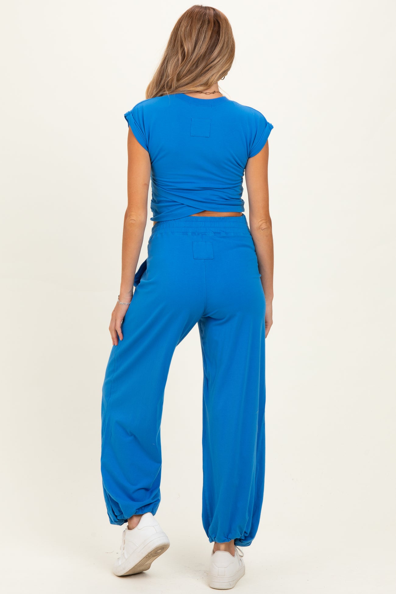 woman wearing a bright blue maternity top and matching maternity jogger pants, showing the back view