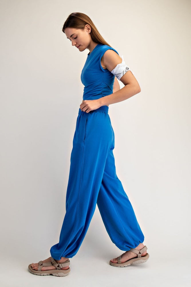 woman wearing a blue two-piece outfit with short sleeves and loose pants, standing sideways