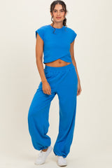 woman wearing a cropped blue t-shirt and matching loose blue pants with elastic cuffs and white sneakers