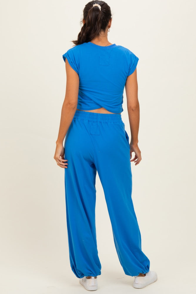 woman wearing a bright blue cropped top and matching loose-fitting pants, seen from the back