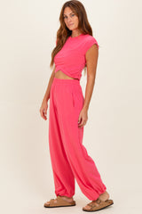 woman wearing a bright pink cropped t-shirt and matching relaxed fit pants with elastic cuffs and side pockets