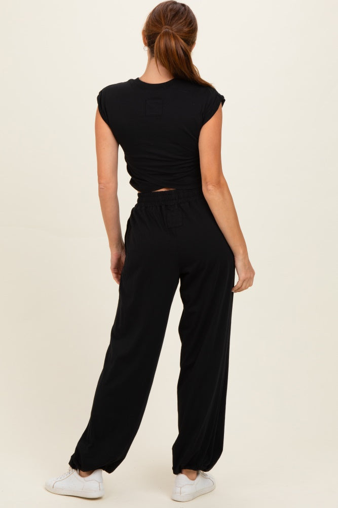 woman wearing a black cropped t-shirt and black loose-fitting pants, facing away from the camera