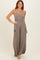 woman wearing a taupe sleeveless maxi dress with a fitted bodice and loose skirt featuring side pockets