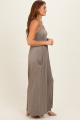 woman wearing a taupe long maxi dress with a fitted bodice and side pockets