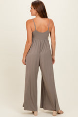 woman wearing a taupe sleeveless jumpsuit with a flowing wide-leg design, viewed from the back