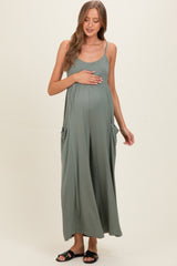 woman wearing a green sleeveless maxi dress with side pockets and holding her baby bump