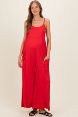 woman wearing a red maternity jumpsuit with a relaxed fit and pockets, showcasing her baby bump