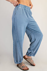 woman wearing light blue fleece lounge pants with side pockets and elastic cuffs, paired with brown slide sandals