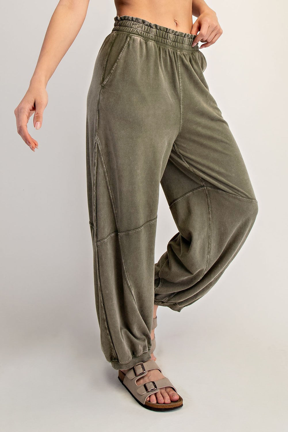 woman wearing olive green relaxed fit sweatpants with a drawstring waist and tapered ankles