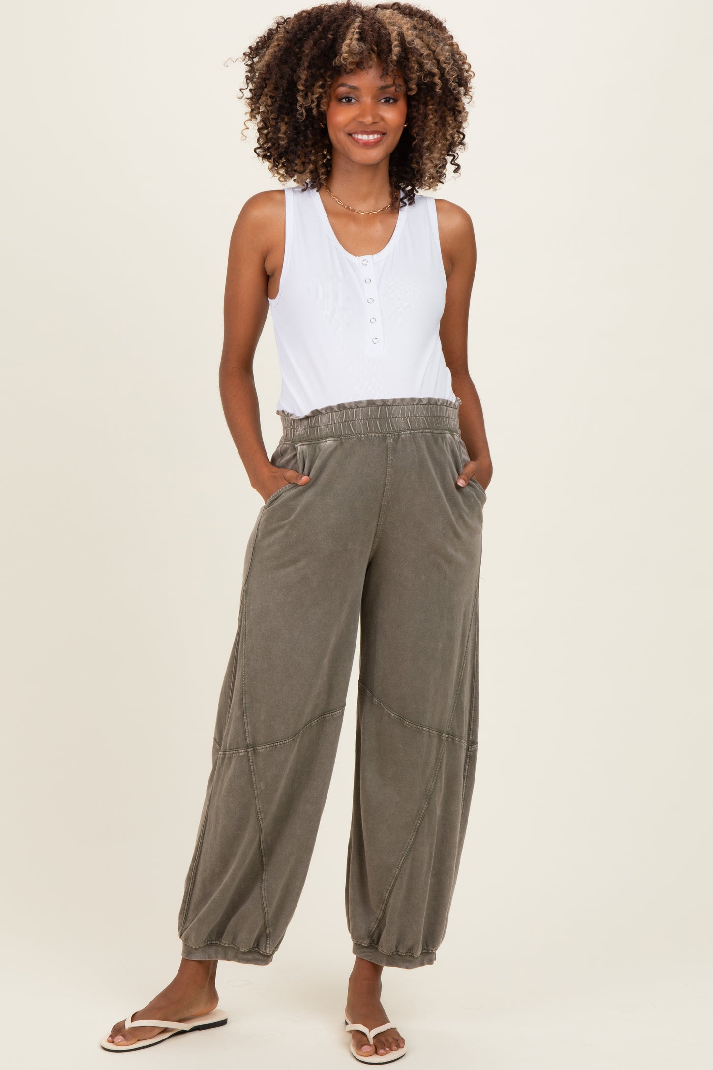 woman wearing a white button-up maternity tank top and olive green maternity jogger pants with pockets