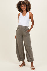 woman wearing a white sleeveless maternity tank top and olive green maternity jogger pants with pockets