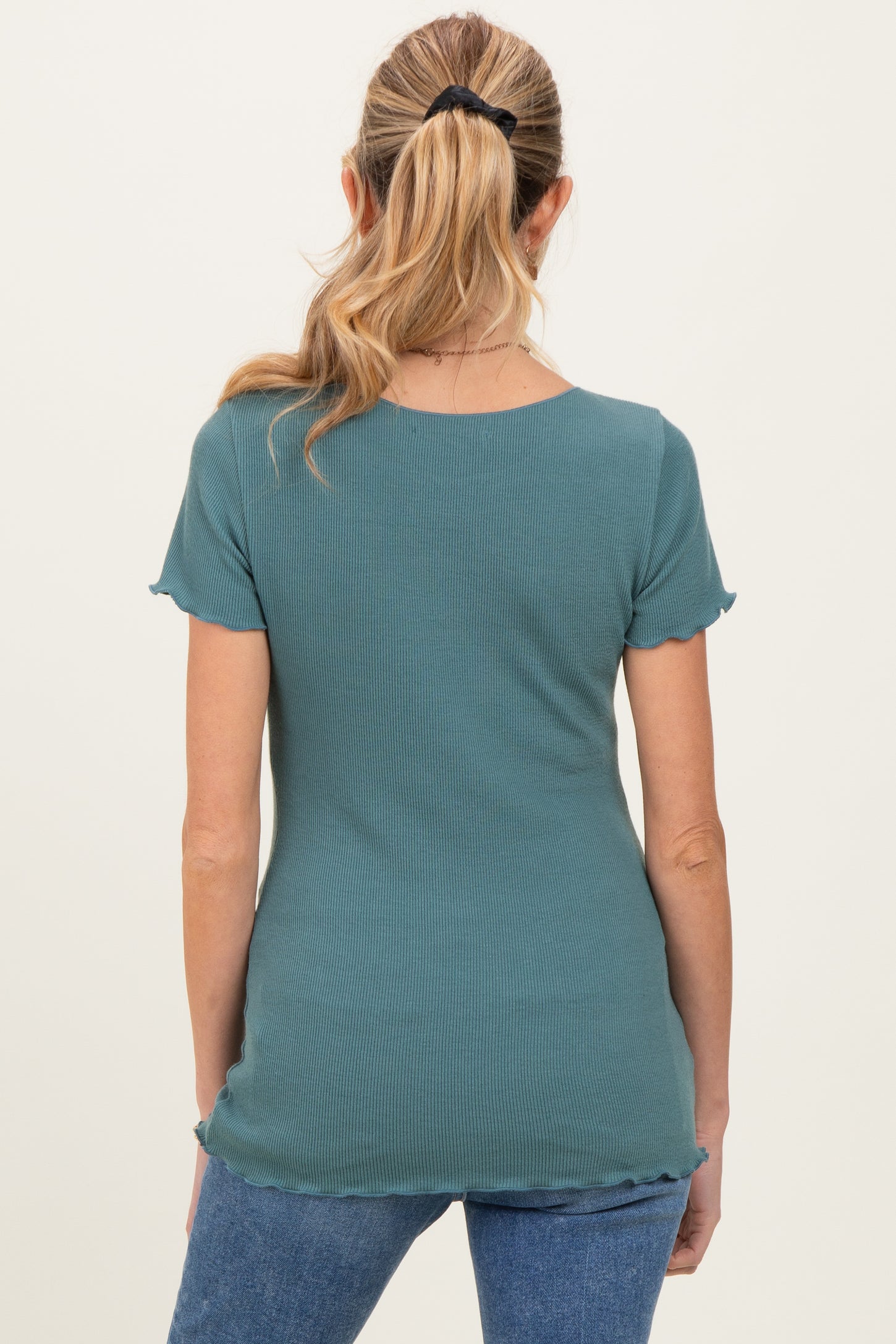 woman wearing a teal maternity top with short sleeves and scalloped hem, viewed from the back