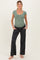 woman wearing a light green ribbed maternity top and dark gray maternity pants with pockets, displaying a baby bump