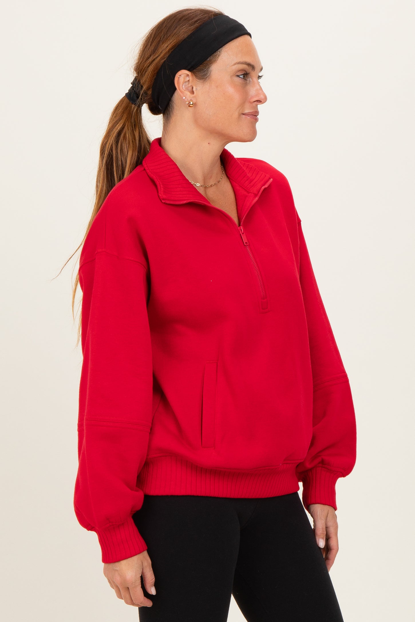 woman wearing a bright red quarter-zip pullover sweatshirt with a relaxed fit and side pockets