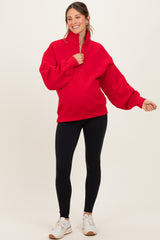 woman wearing a red maternity pullover sweatshirt with a half-zip and balloon sleeves, paired with black leggings and sneakers